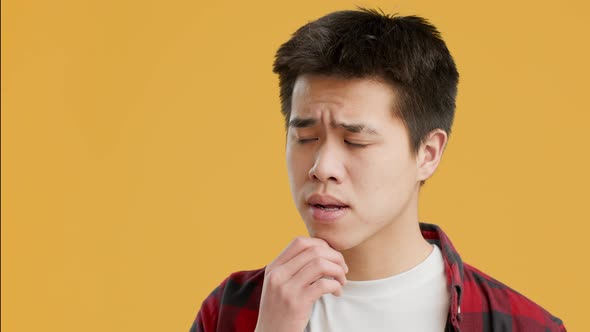Asian Guy Thinking About Problems And Frowning Over Yellow Background alt