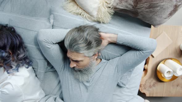 Angry Mature Man Looking at Sleeping Wife Then Smiling and Turning Away alt