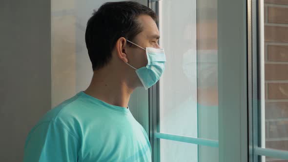Sad Man in a Medical Mask Look at the Window