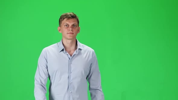 Young Man in a Gray Shirt Going and Looking Forward Against a Green Background. Slow Motion. alt