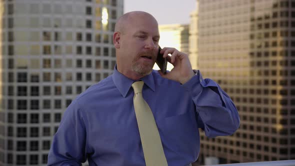 Businessman using cell phone on rooftop in city