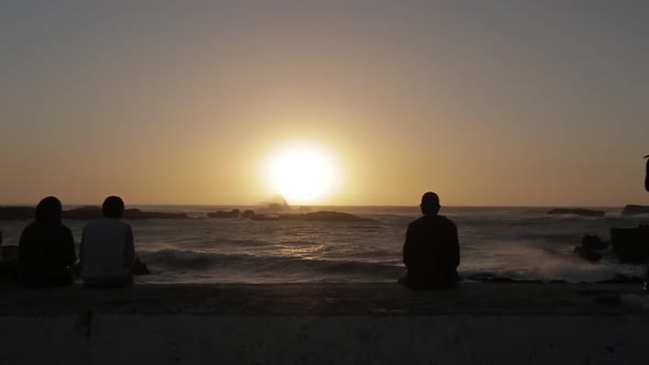 Young people sitting in front of the beach watching the sunset in Essaouira alt