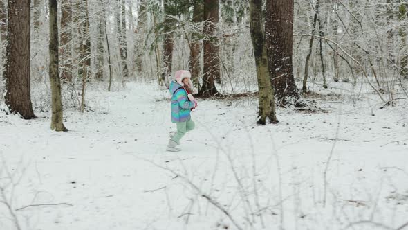Cute Child Girl in a Colorful Clothing Running in a Snowy Winter Park