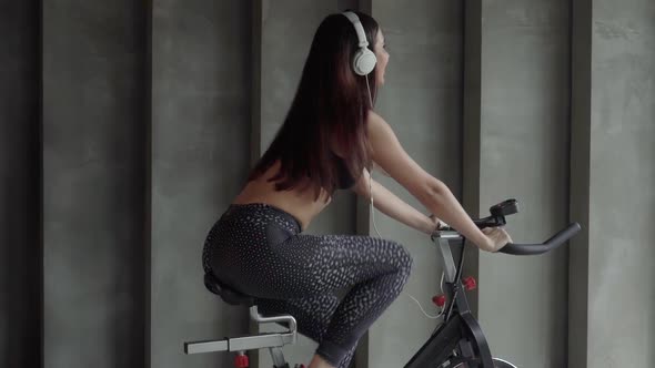 Young Woman Cycling on Gym Machine Bicycle 