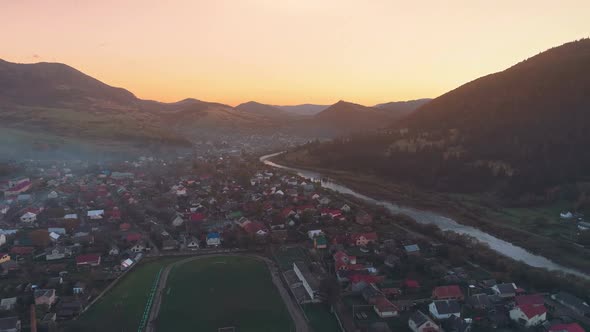 Pictorial Town Buildings Against Hills Hiding Setting Sun alt