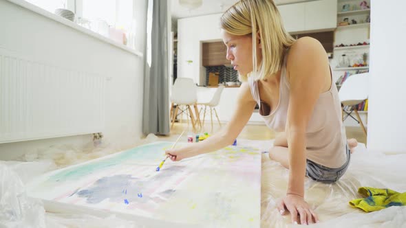 Creative Young Woman with Loose Fair Hair Draws on Canvas