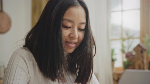 Smiling Asian Woman Portrait with Braces While Working on Her Laptop in Slow Motion alt