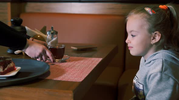 Little Girl is Served Dessert with Fresh Strawberries and Tea on a Tray alt