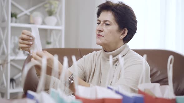 Side View of Dazed Brunette Middleaged Woman Looking at Bills Holding Head in Hands alt