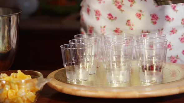 Chef Is Laying Syrup with Cherry on Bottom of Glasses for Dessert Cooking alt