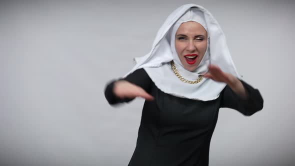 Joyful Carefree Woman in Nun Costume Having Fun at Grey Background Stretching Hands Aside Smiling alt