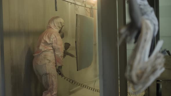 Worker in Protective Suit Sprays Powder Paint From Gun on Metal Products alt
