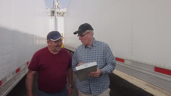Truck drivers looking over clipboard together.  Fully released for commercial use.