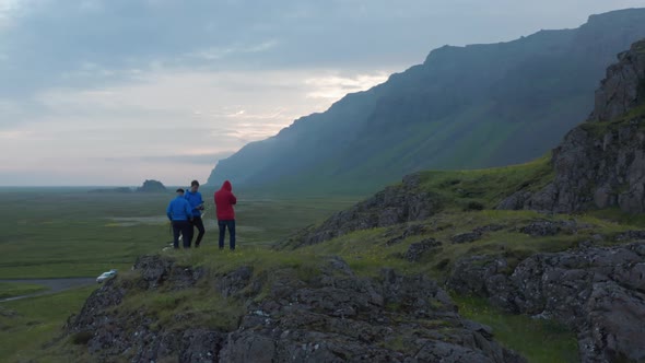 Birds Eye Orbit of Three People Tourist on Top of Peak in Iceland Highlands Taking Picture Amazing alt