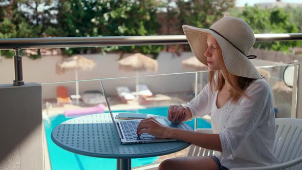 Woman Talks Online Using Laptop in Hotel with Swimming Pool on Summer Vacation