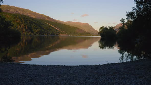 Peaceful little bay on Llyn Padarn Lake during sunset, beautiful reflection on water surface, Snowdo alt