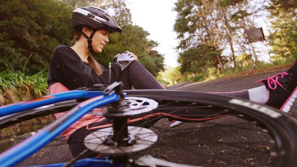 Female mountain biker sitting on ground in pain alt