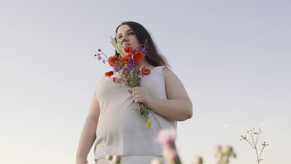 Body Positive Woman with a Bouquet in a Field of Wild Flowers alt