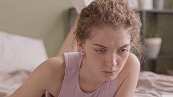 Young Woman Drawing on Tablet with Pen in Bed alt