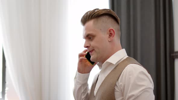 Young Man in Vest From Threepiece Suit Angrily Listens to What They Say to Him on Phone alt