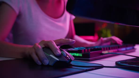 Woman Gamer Hands Using Wired Computer Mouse and Typing on Neon Keyboard Playing Video Games at alt