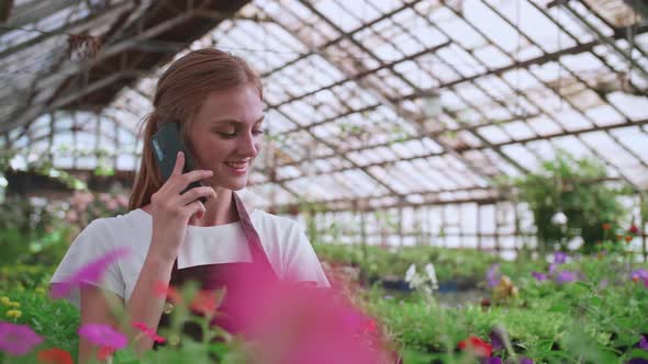 Close Up Portrait of Beautiful Joyful Female Florist Store Manager Talking on Cellphone About Plant