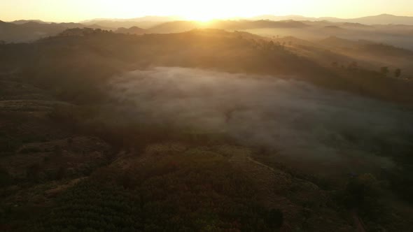 4K aerial view over a misty mountainous area. The great golden sun in the morning alt