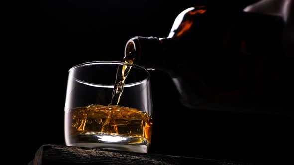 Whiskey Pouring in the Glass From the Bottle. With Ice Cubes. alt