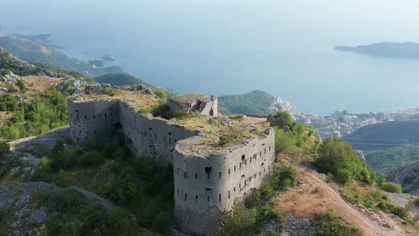Ruin of an old stone fortress on the top of the hill, overlooking the coast and sea alt