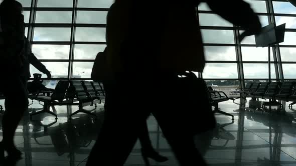 Travelers Walking Along Window in Airport Terminal, People Silhouettes Walking. alt