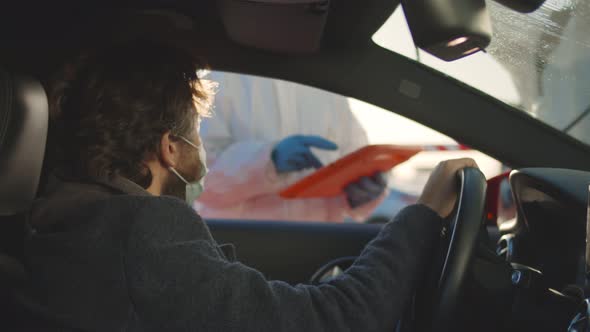 Man Driver at Checkpoint Giving Information To Guard While His Car Being Disinfected alt