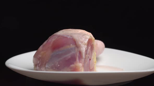 chicken leg or thigh with shin lies on white plate and rotates on turntable alt
