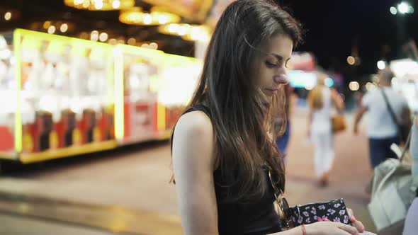 Brunette Woman Counting Cash, Waiting on the Line To Buy Carnival Tickets  alt