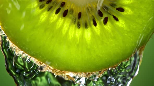 Super Slow Motion Macro Shot of Flowing Water From Kiwi Slice on Green Background at 1000Fps alt