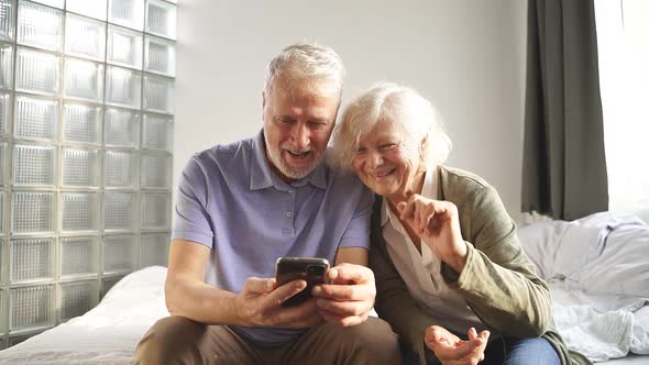 Happy Elderly Couple Using Their Smartphone Make a Video Call with Friends and Family alt
