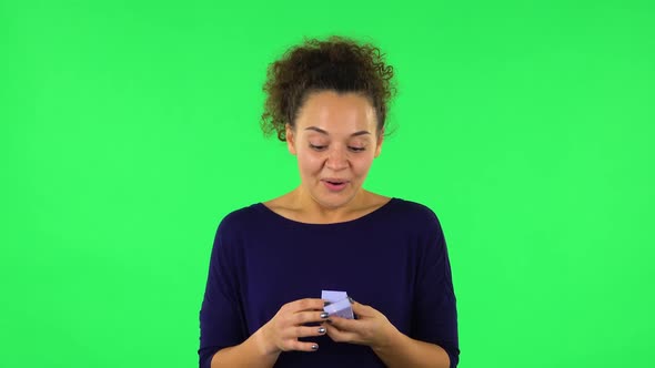 Portrait of Curly Woman Opening Small Box with a Surprise and Very Rejoicing . Green Screen alt