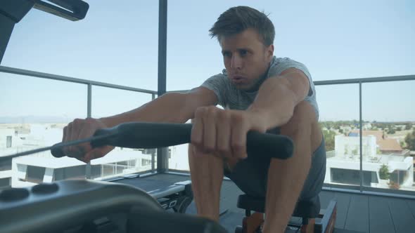 Man exercising with a rowing machine on a rooftop