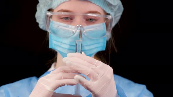 Professional Female Doctor Holds a Syringe with a Vaccine on a Black Background alt