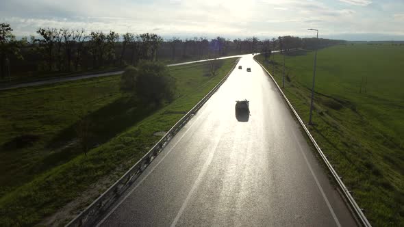 Drone Above Wet Asphalt Road for Cars Between Sown Fields alt