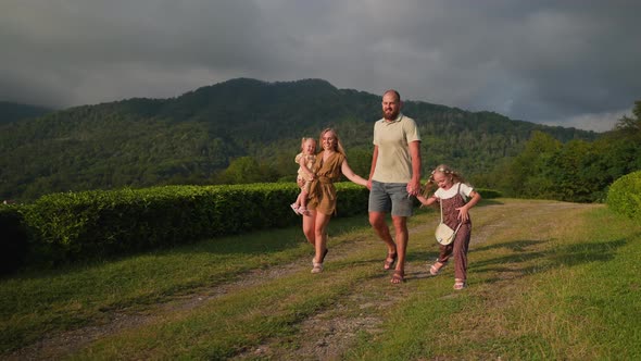Portrait of Happy Family Pair with Two Daughters in Nature Family is Walking in Highlands alt