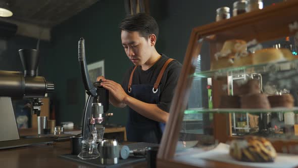 4K Asian man barista making hot espresso shot from flair espresso coffee maker alt