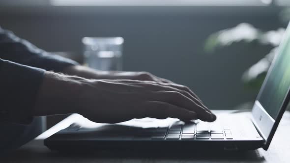 An Unrecognizable Man Uses a Laptop to Hack Into Other People's Accounts alt