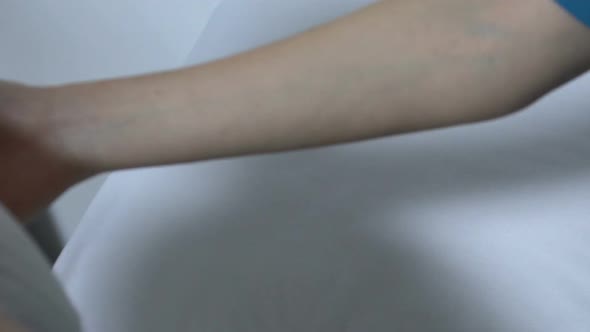 Nurse Helping Old Woman to Lay in Hospital Bed, Lady Feeling Weak After Surgery alt