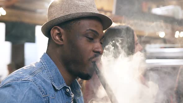 African Young Man Smoking Hookah in the Bar alt