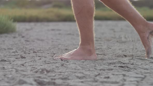 Man Walking Barefoot on Bottom of Dried Lake or Cracked Soil Ground