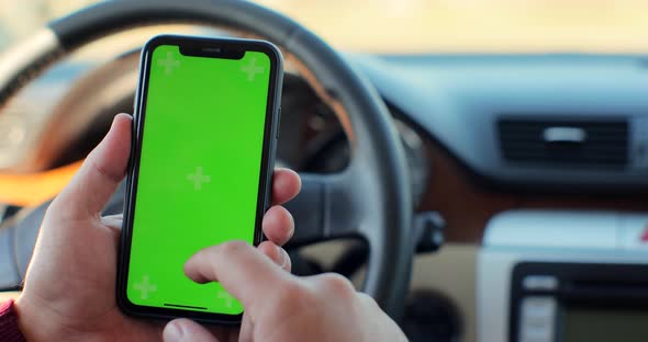 Man Hand Using Chromakey Mobile Phone with Empty Green Screen in Modern Car alt