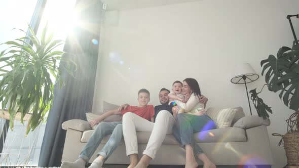 Happy Family Mom Dad and Cute Kids Relaxing on the Couch Laughing Having Fun Watching Tv alt