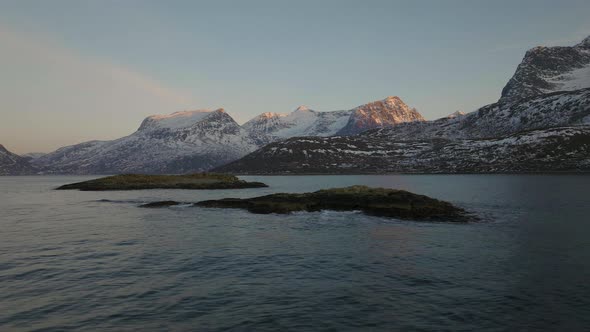 Rugged beauty of snowy arctic mountains, oystercatchers in flight; aerial alt