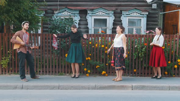 Young Women Dancing Folk Dances on the Street in the Village By the Music - a Man Playing Balalaika alt