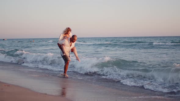 Couple of Young Lovers Holding Hands Walking Along the Beach By the Sea